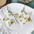 Primer plano de pendientes de cuero en forma de estrella con estampado de girasol en plato - Estampado Estrella Girasol (1)