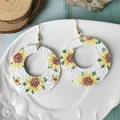 Pendientes de girasol bohemios en cuero brillante con ganchos dorados sobre un plato decorado - Estampado Redondo Girasol (3)