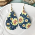 Detalle de pendientes de gota de cuero con motivo de girasol sobre un plato blanco - Estampado Gota Girasol Azul (5)