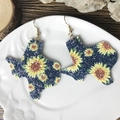 Detail of Texas map earrings with sunflower pattern on a white ceramic plate - Texas Map Sunflower-Blue Glitter (2)