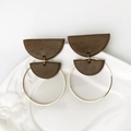 Detail of geometric brown clay earrings with gold hoops on a white relief plate - Dark Brown