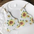 Nahaufnahme glitzernder Ohrmarke-Ohrringe mit Sonnenblumenmuster auf weißem Keramikteller - Stier Ohrmarke Sonnenblume-Weiß Glitzer (5)