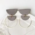 Minimalist geometric polymer clay earrings with golden metal rings on a ceramic plate - Gray