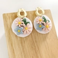 Detail of handmade clay floral earrings with pink and blue flowers on textured wood - Gold Ring Pink Yellow Flower White Round Pendant (3)