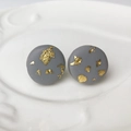 Detailed close-up of handmade gray clay stud earrings with gold foil on a white plate - Gray (4)