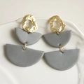 Detail of semi-circle layered clay earrings with hammered gold metal discs in a ceramic dish - Gray