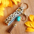 Dettaglio del portachiavi in pelle leopardata con ciondolo turchese e nappe marroni - Stampa Leopardata (Placcatura Oro 3)