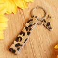 Detail of leopard print leather keychain with silver metal ring on rustic wooden background - Dark Leopard Style