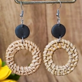 Detail of woven rattan earrings featuring black round studs on a rustic wood background - Dark Brown Disc Round Rattan Style (5)