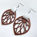 Detailed macro view of leaf-shaped cutout wooden earrings with white leather accents - White