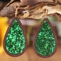 Macro shot of Halloween teardrop earrings with green glitter and dark wood frame - Green Sequin Style