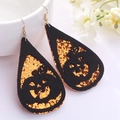 Detalle de pendientes de calabaza en cuero brillante naranja y negro sobre fondo floral blanco - Calabaza