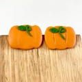 Detailed close-up of handmade orange pumpkin polymer clay earrings on a wooden stand - Pumpkin (3)