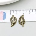 Detailansicht zweier antiker Bronze-Blattanhänger mit feiner Maserung und 22mm Maßstab - Antike Bronze Blatt (3985)