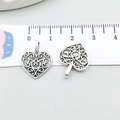 Macro di due ciondoli a cuore in argento antico con righello per mostrare le dimensioni - Cuore Traforato Argento Antico (6297)