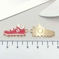 Macro shot of red enamel soccer cleat charm with golden metal back and scale reference - Enamel Baseball Shoe Style (19639) / Red