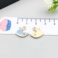 Detailed view of enamel whale pendants showing front and back with a measuring ruler - Whale / Lake Blue