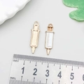 Golden and white enamel syringe charm for DIY jewelry making showing size with a ruler - White Enamel Syringe 9*30mm (12005)