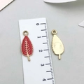 Red enamel leaf pendant in gold finish showing both sides on a measurement scale - Thanksgiving Leaf (19211)