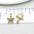 Makroansicht von 10mm Vintage-Gold-Blumenanhängern auf einem weißen Maßband - Antikgold Blumen-Stil (11080)
