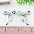Pair of silver polished bow charms for DIY jewelry making with 20mm width and top loop - Curved Bowknot (21403)