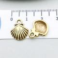 Dettaglio del ciondolo a conchiglia in oro antico con scanalature accanto a un righello - Guscio (11082)