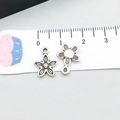 Macro shot of silver sunflower pendants with petal textures on a white scale ruler - Antique Silver Small Flower (4367) / 1 Piece (11x14mm) / Antique Silver