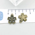 Detail view of 15mm antique bronze flower pendants showing size on a ruler scale - Cherry Blossom (20481)