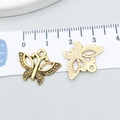 Vue détaillée de breloques papillon en or antique ajouré à côté d'une règle graduée - Papillon Or Antique (10215) / Or antique