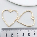 Detail of two gold heart-shaped hollow metal alloy pendants for DIY jewelry making - Heart Frame