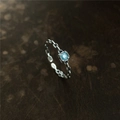 Gros plan d'une bague en argent S925 avec pierre bleue et design de chaîne tressée - Bleu clair