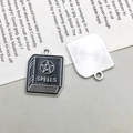 Macro detail of alloy book pendant with black enamel finish and SPELLS engraving - Enamel Spell Book