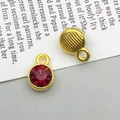 Close-up of double-sided gold alloy pendants with red faceted stone and textured back - January-Red
