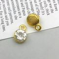 Detail of round gold charms with crystal center showing textured back and hanging loop - April-Clear