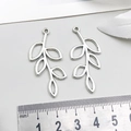 Macro shot of silver alloy hollow leaf pendants with measurement scale for DIY jewelry - Branch Style (2495)