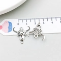 Detail view of retro silver bull skull pendant with tribal carvings next to a ruler - Antique Silver Halloween Skull Bull Head (10865)