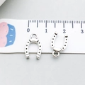 Silver horseshoe charms for DIY jewelry making shown with measuring tape for size - Horseshoe Shape (19238)