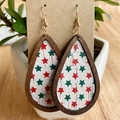 Macro detail of teardrop wooden earrings with festive red and green star prints on white cork - Red Green Star Pattern (1)