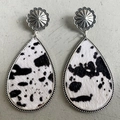 Close-up of teardrop leather earrings with cow print pony hair and floral metal studs - Black And White Cow Print Style (2)
