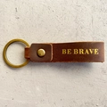Détail du porte-clés en cuir marron avec gravure Be Brave et anneau en bronze - Style BE BRAVE (1)