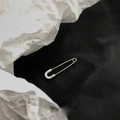 Pendientes de imperdible en plata S925 pulida sobre fondo de cuero y papel arrugado - Estilo de Alfiler de Seguridad / Plateado