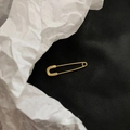 Primer plano de pendiente de imperdible dorado con sello de plata de ley S925 - Estilo de Alfiler de Seguridad / Dorado