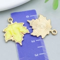Détail macro d'un pendentif feuille d'érable sur une règle montrant la taille de 2,5 cm - 19*24mm / Feuille d'Érable en Émail Jaune (14250)