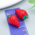 Detailed macro view of red acrylic strawberry charms with silver rings and measuring scale - Red Strawberry Style
