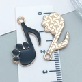 Macro view showing black enamel music note and cat paw charms on a measuring ruler - Black Cat Claw Note (18552)