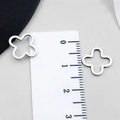 Close-up of 1.2cm hollow four-leaf clover stainless steel pendants on a scale ruler - Four-Leaf Clover Style