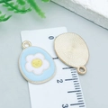 Light blue enamel Easter egg pendant with white flower and yellow smiley face pattern - Cyan Frangipani Egg (25126)
