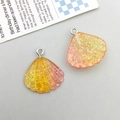 Macro shot of glittery resin shell charms with silver rings for DIY jewelry making - Yellow Gradient