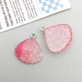 Close-up of pink glitter resin shell charms for DIY jewelry making with silver rings - Pink Gradient