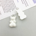 Close-up of white resin bear DIY pendants with silver metal rings on newspaper background - White Resin Bear (12576)